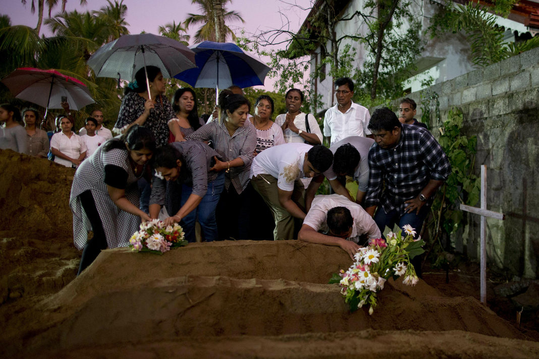 as-isis-claims-responsibility-for-sri-lanka-church-bombings-official-claims-retaliation-for-nz-mosque-massacre Relatives place flowers after the burial of three family members who died in an Easter Sunday bomb blast at St. Sebastian Church in Negombo, Sri Lanka, on Monday. GEMUNU AMARASINGHE / AP