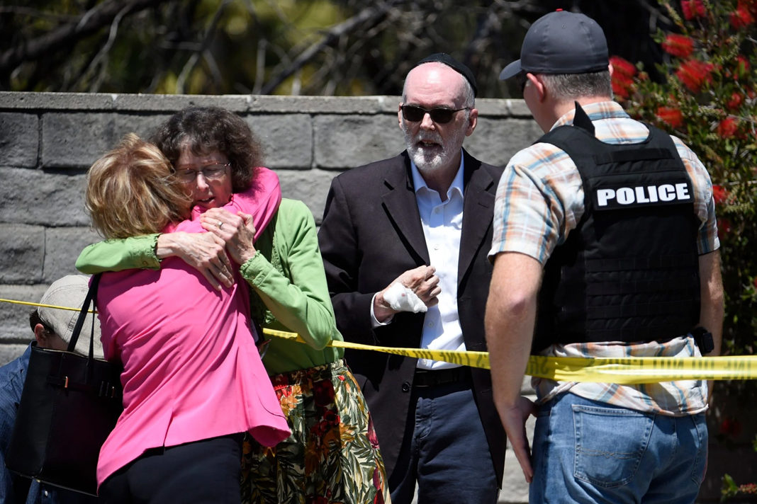 Two people hug as another talks to a San Diego County Sheriff's deputy outside of the Chabad of Poway Synagogue Saturday, April 27, 2019, in Poway, Calif. (AP/Denis Poroy)