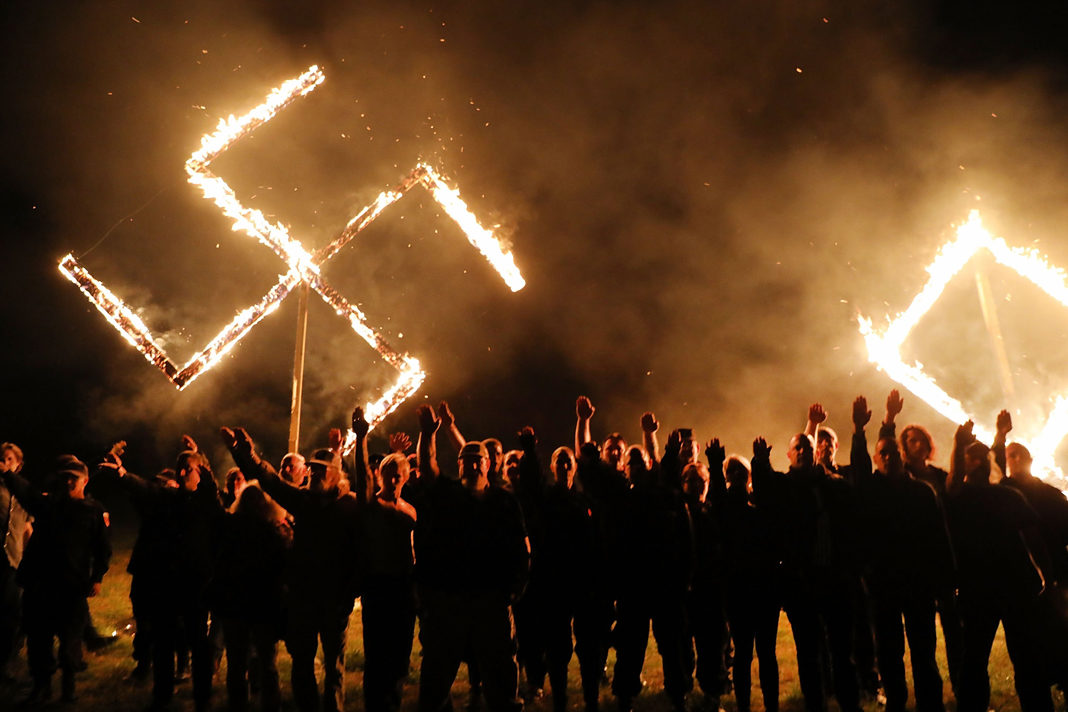 anti-semitic-attacks-spike-killing-highest-number-of-jews-in-decades Illustrative: Members of the National Socialist Movement, one of the largest neo-Nazi groups in the US, hold a swastika burning after a rally on April 21, 2018, in Draketown, Georgia. (Spencer Platt/Getty Images/AFP)