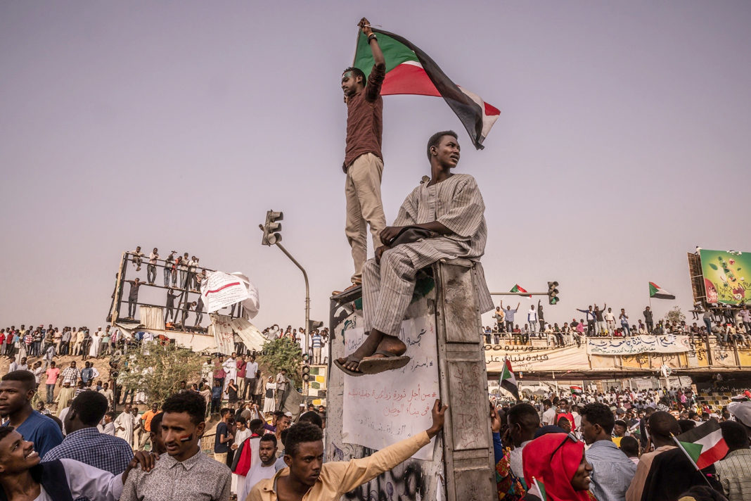 pray-for-a-real-change-say-christians-in-sudan A protester flies a flag of Sudan in Khartoum. / Twitter @Malmakiyat, Bryan Denton