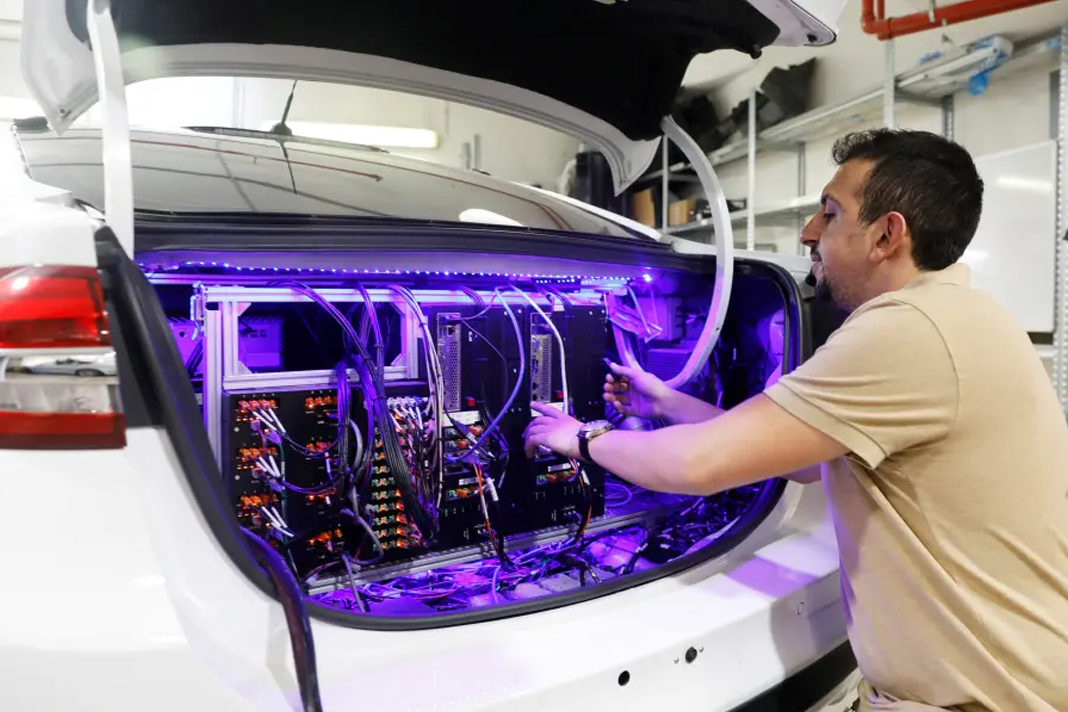 A worker tends to systems in the back of a Mobileye autonomous driving test vehicle, at the Mobileye headquarters in Jerusalem, May 15, 2018.. (photo credit: REUTERS)