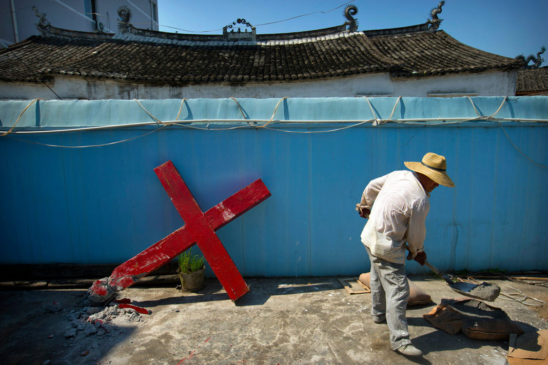 chinese-government-to-offer-compensation-after-church-demolition A church member shovels cement mix preparing to re-mount a cross on a Protestant church, which had been forcibly pulled down by Chinese government workers in Taitou Village, eastern China, July 29, 2015.