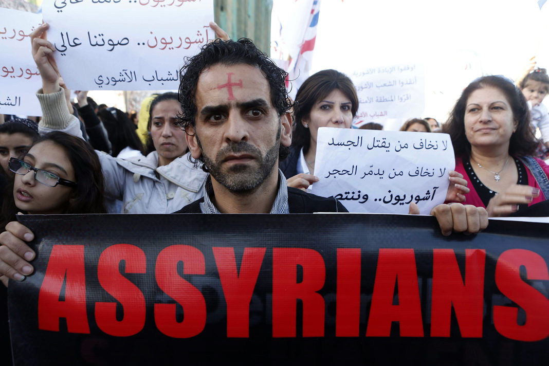 Assyrians hold banners. Reuters/mohamed azakir.